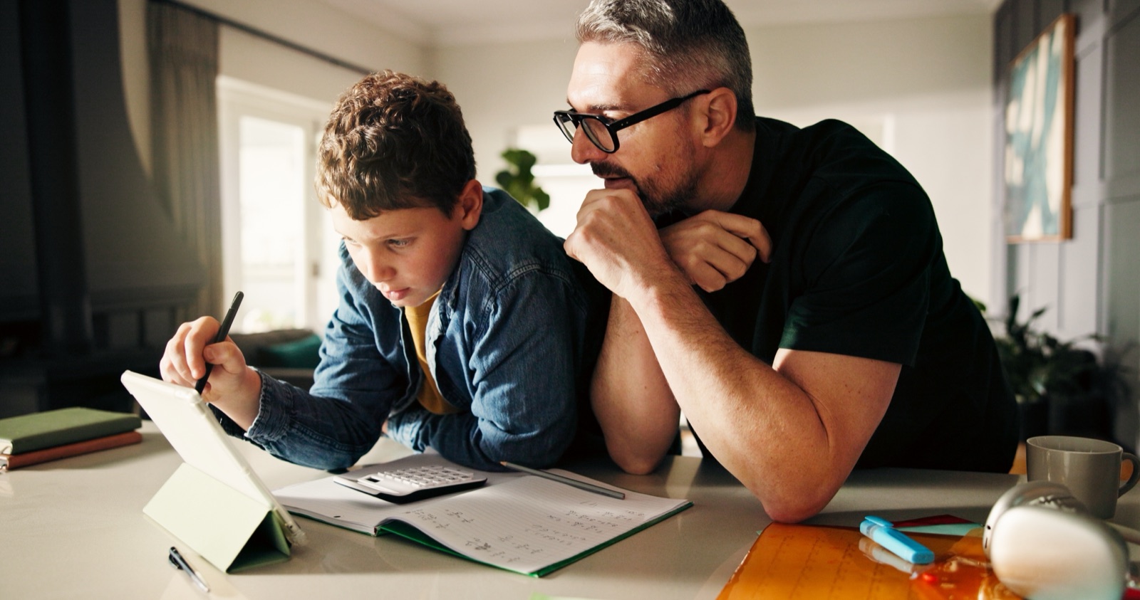 Parent helping a child practice math on a tablet at home