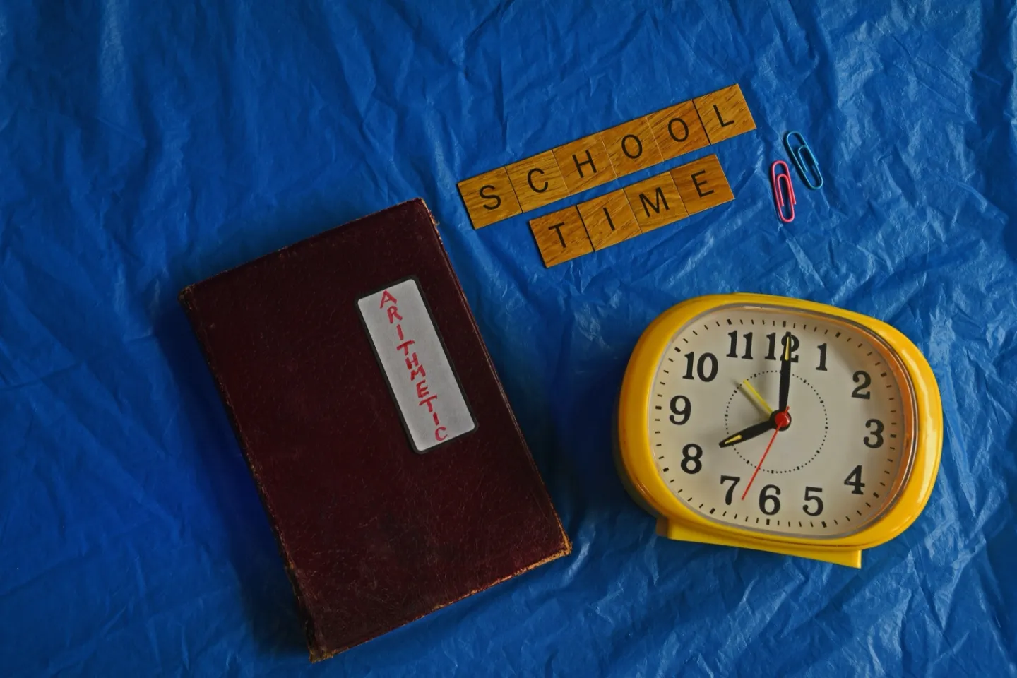 Analog clock beside an open arithmetic practice book
