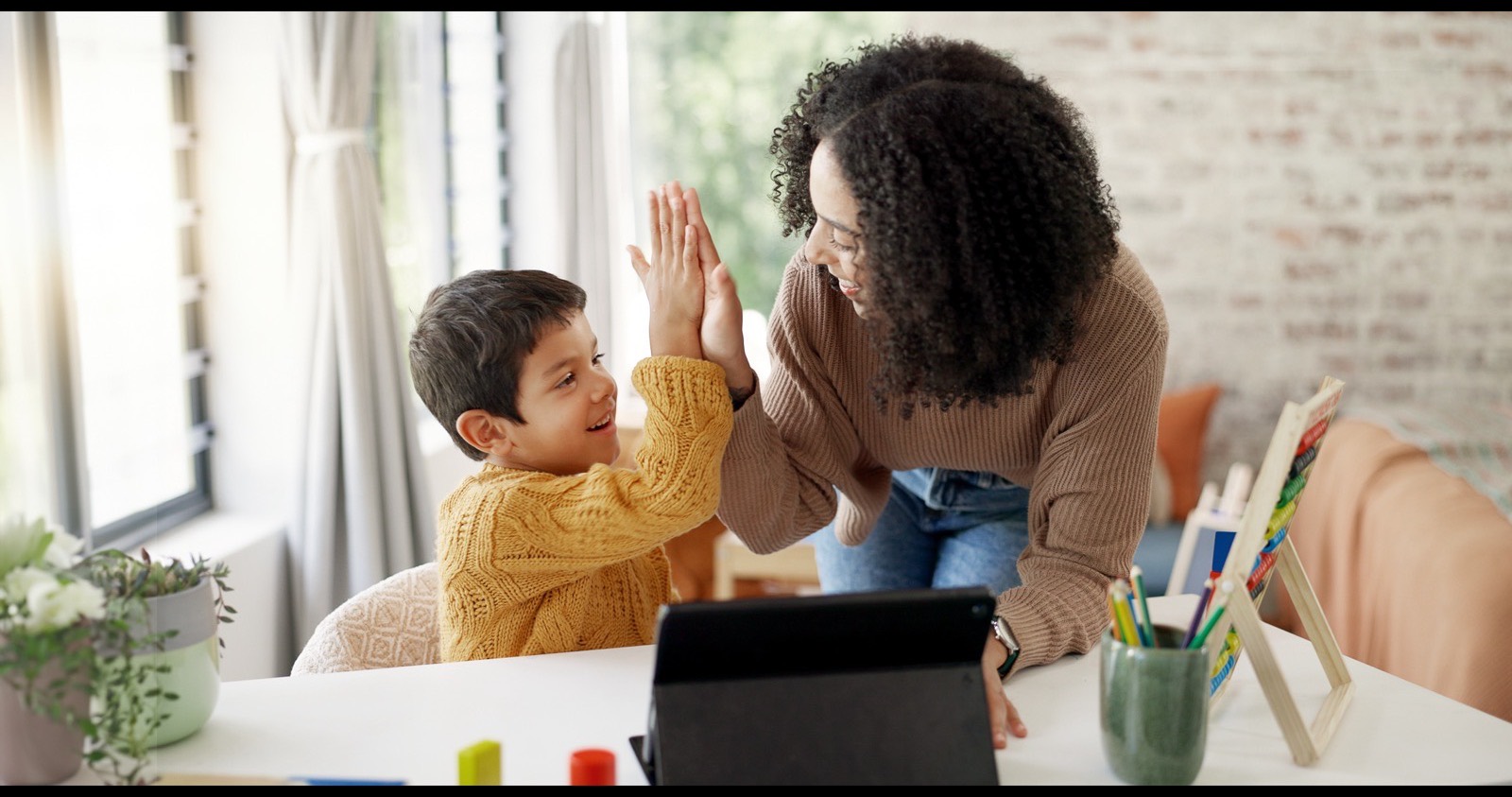 Mother high-fiving her son after finishing a math fact practice session on a tablet