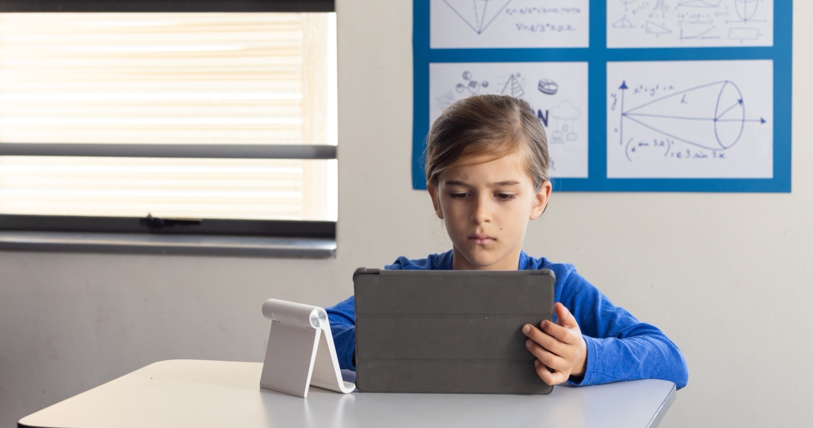 Elementary student practicing math facts on a tablet at a classroom desk