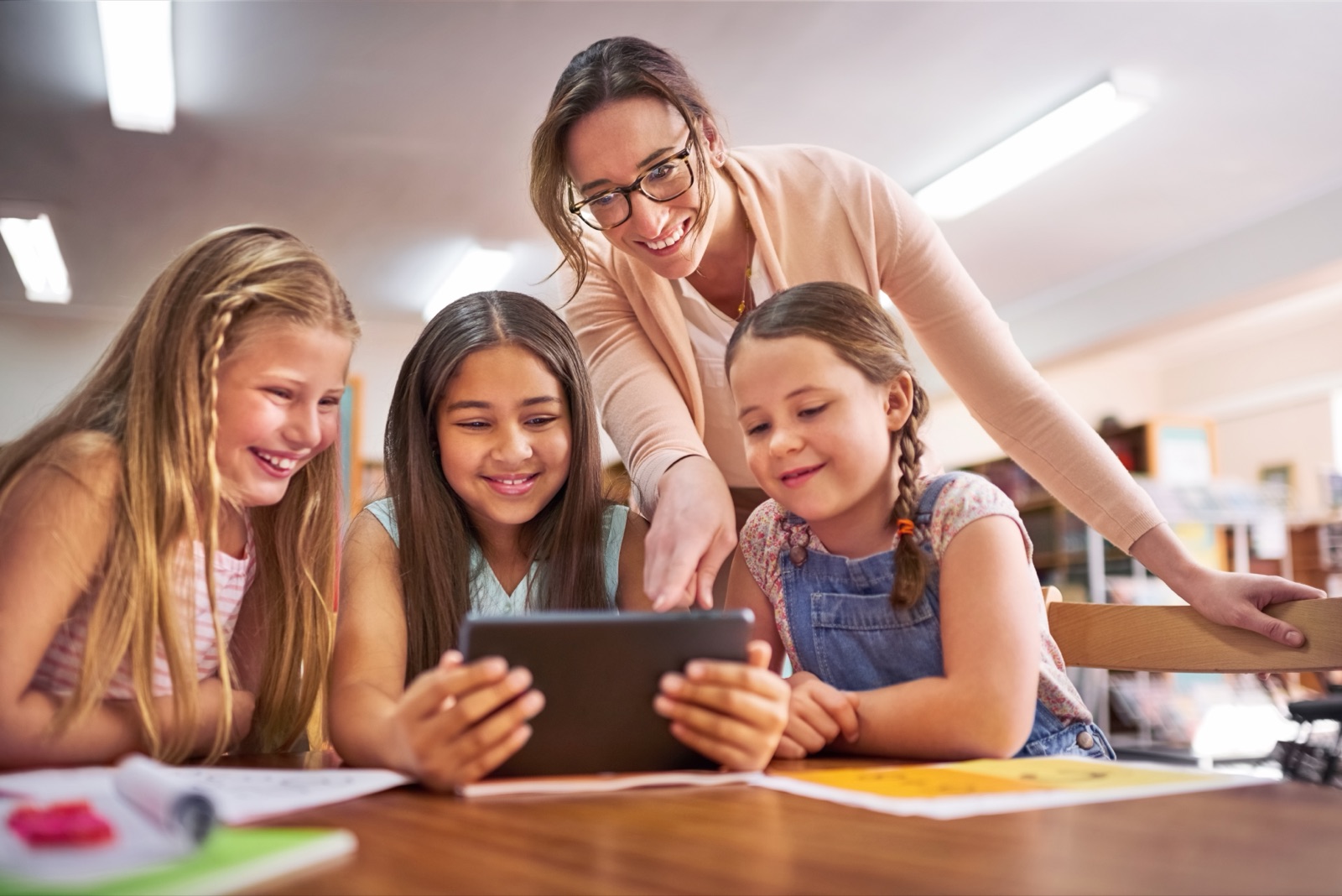 Teacher helping children use a tablet for a math learning app